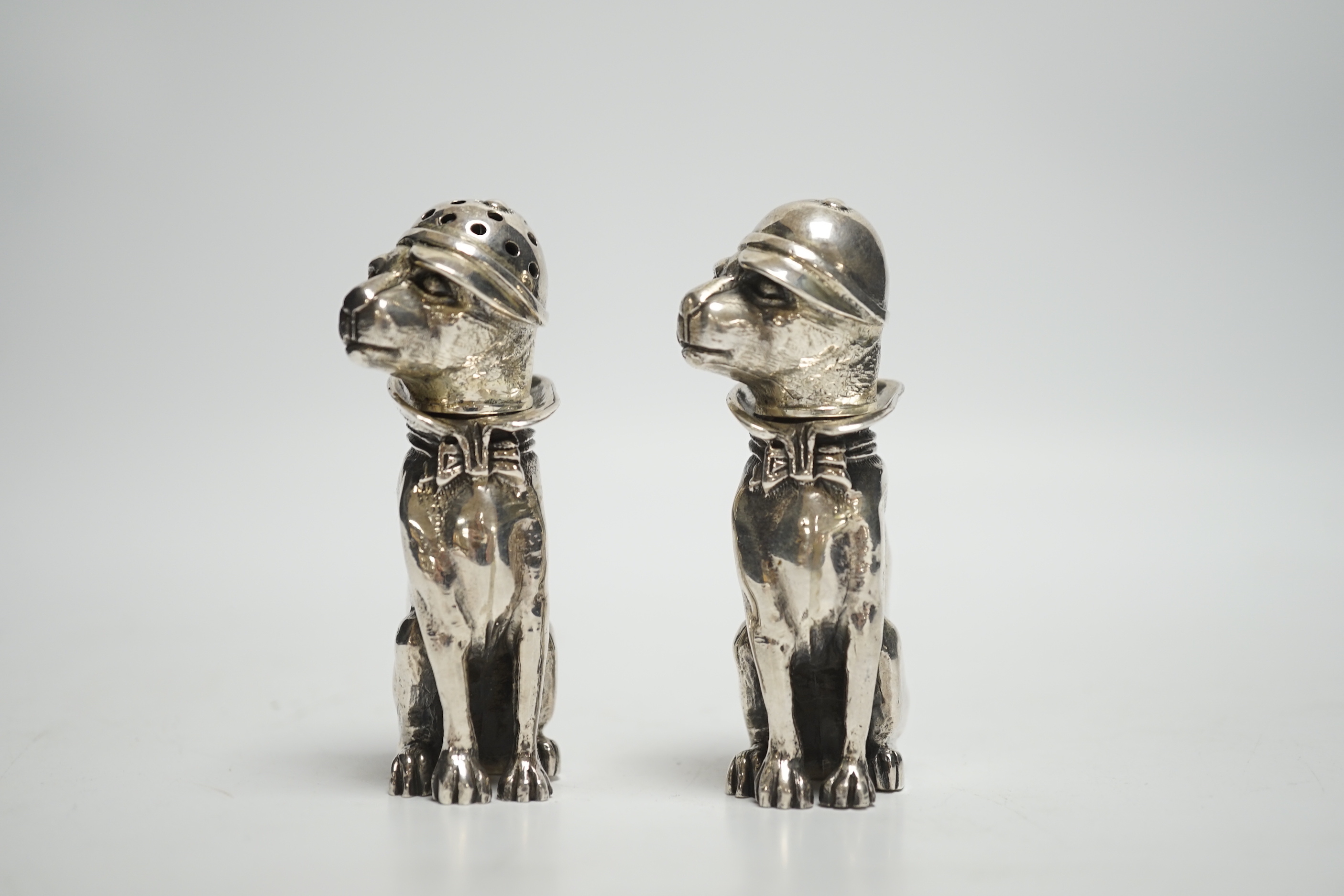 A novelty pair of 925 pepperettes, modelled as seated dogs, wearing caps, 76mm, 6.3oz.